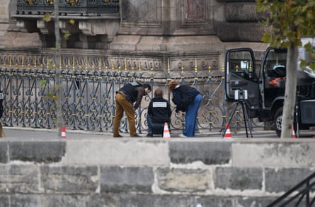 Investigators crouch beside railings outside the museum