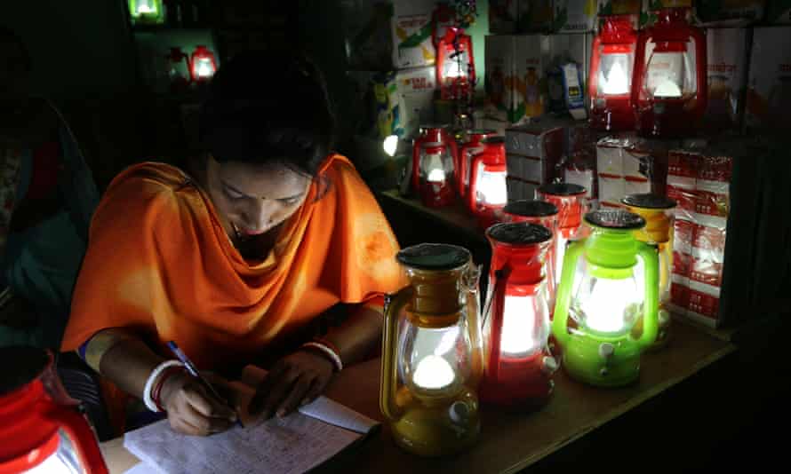 Woman works by solar-powered lamplight
