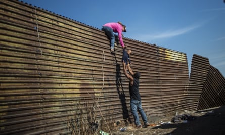 A group of migrants climb the fence separating Mexico from the United States.