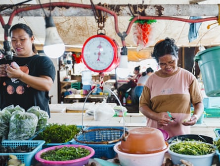 Two Filipinas prepare a seaweed at a market stall