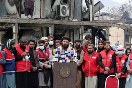 Mohammad Nabi Omari speaks at a podium while rescue teams stand behind him.