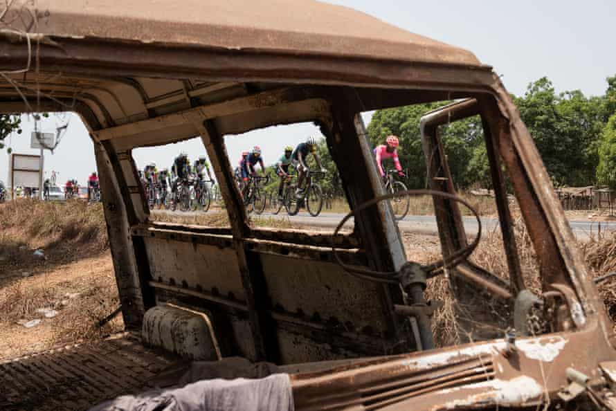 Riders pass a burnt-out car on the road from Freetown to Lunsar.