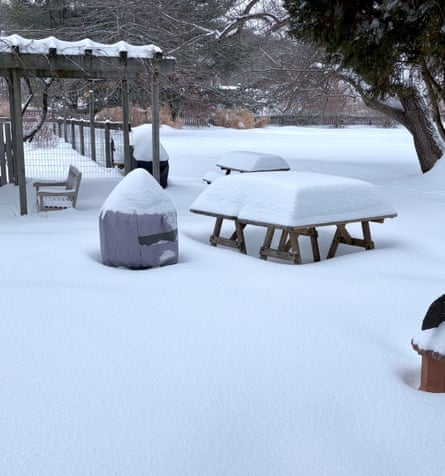 Snow piled on the ground, a pergola and picnic tables