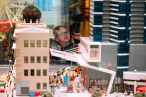 A young child wearing glasses pointing up at a Lego tower