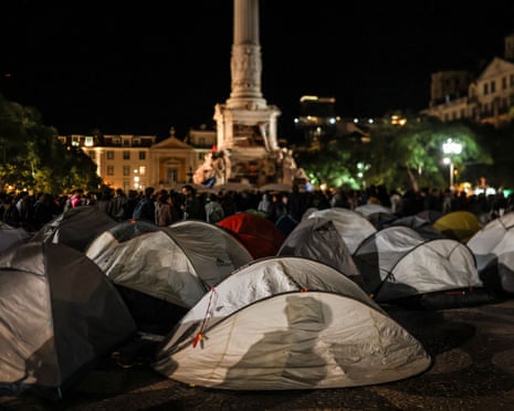 Dozens of tents fill Lisbon's Rossio square at night during a housing protest