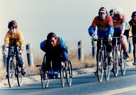 people ride bikes next to a man in a wheelchair