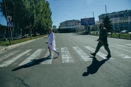 Tetiana and Oleksandr crossing a street beneath anti-drone netting in Kramatorsk.