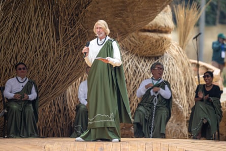 A man wearing a green robe gives a speech on a stage