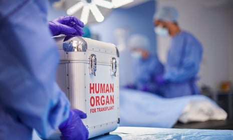 A stock image of an hospital operation being performed, while in the foreground there is a metal box marked 'Human organ for transplant'.