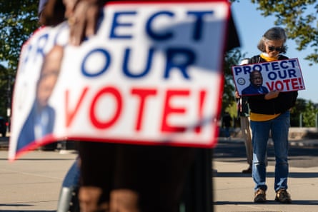 People holding signs that say “Protect Our Vote.”