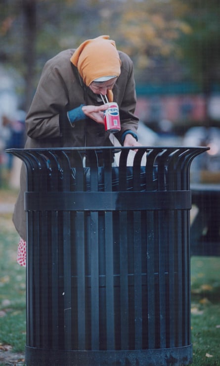 An elderly woman finds something to eat and drink in a garbage can on York Quay, Toronto.
