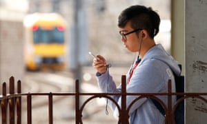 A commuter uses a mobile phone while wearing headphones at Central Station in Sydney, Australia