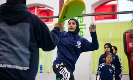 A muslim woman moves to kick as she trains in Taekwondo.