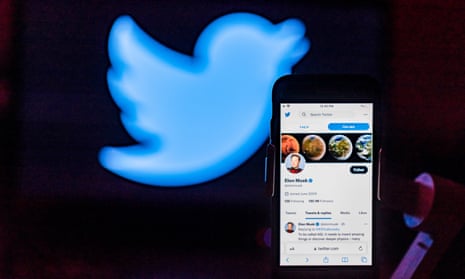 Elon Musk's twitter account is seen displayed on a mobile phone screen with the twitter logo on the background