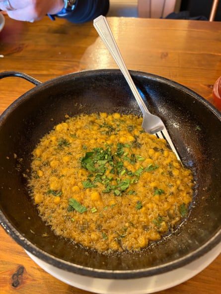 A dark bowl full of cooked lentils and coriander in sauce