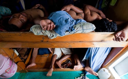 Men sleeping in cramped wooded bunks on a boat