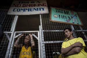 prisoners wait by the no smoking sign