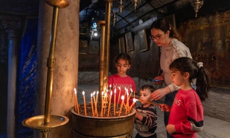 Los niños encienden velas en la desierta Iglesia de la Natividad en Belén.