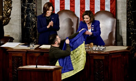 Volodymyr Zelenskiy entrega uma bandeira ucraniana assinada por soldados em Bakhmut à presidente da Câmara dos EUA, Nancy Pelosi, à direita, durante uma reunião conjunta do Congresso com a vice-presidente dos EUA, Kamala Harris.