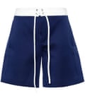 A pair of long baggy, dark blue shorts with a white drawstring waistband