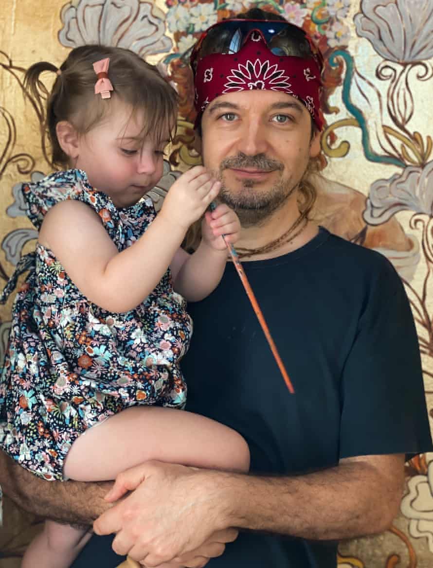 Akos Juhasz with his daughter in front of the gold leaf mural he created inside the Cistern Chapel