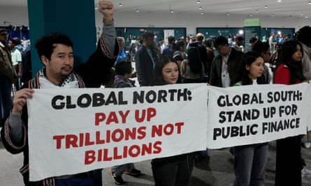 People hold signs saying 'global north: pay up trillions not billions' and 'global south: stand up for public finance'