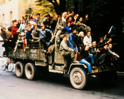 Czechoslovakian army trucks taking youngsters around the city as Soviet tanks halted on the outskirts and began siege of Czech army barracks. The youngsters wave Czechoslovakian National flags and chant national song and patriotic slogans.