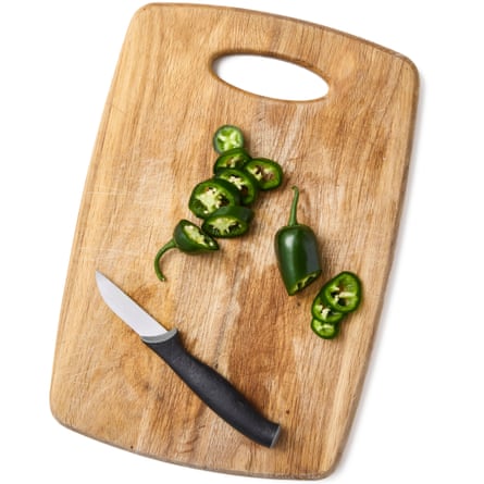 A knife and chopped jalapeños on a chopping board.