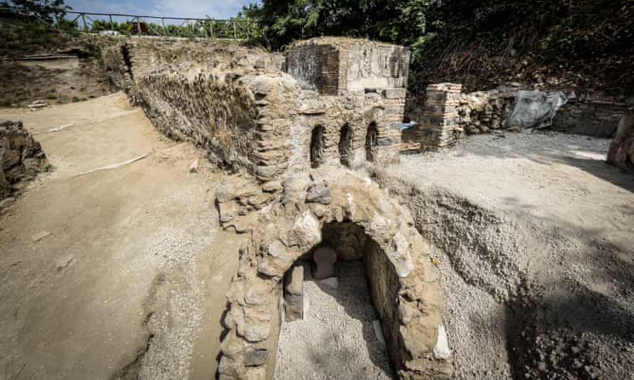 La tombe présente une façade décorée de plantes vertes sur fond bleu et une salle d'inhumation