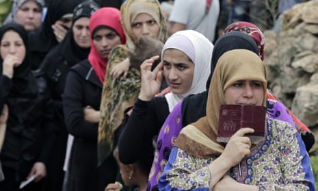 Syrian women queue to receive aid at a refugee camp in the town of Ketermaya, Lebanon. 