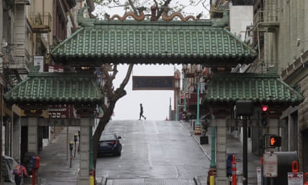 A pedestrian crosses Grant Street behind the Dragon Gate, an entrance to Chinatown in San Francisco.