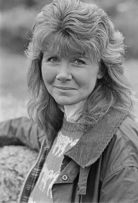 A black and white photo of a woman wearing a jacket and jumper, with high blow-dried hair