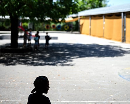 Children sheltering under tree in concrete playground
