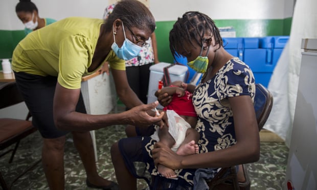A healthcare worker vaccinates 2-year-old Michaelle Laguerre at a malnutrition clinic run by Unicef in Les Cayes, Haiti, on 26 May.