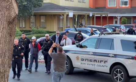 Police officers detain a man, whom law enforcement believes is the suspect in the mass shooting, in Half Moon Bay.