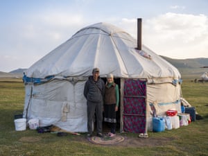 A nomadic couple pose in front of their yurt