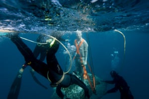Divers ensure the sculpture makes a safe descent
