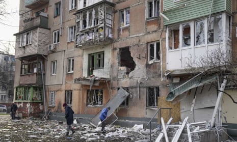 People walk next to an apartment building hit by shelling in Mariupol, Ukraine, on Monday 