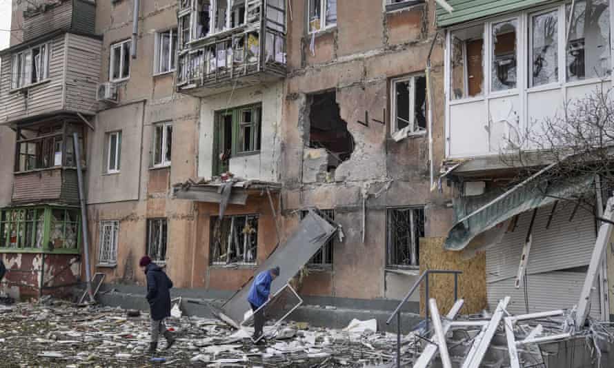 People walk next to an apartment building hit by shelling.