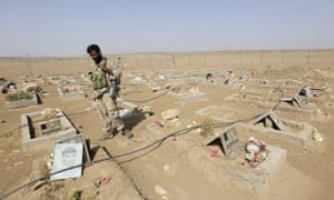 A soldier stands next to graves of Houthi fighters in Yemen