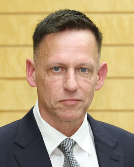 A head-and-shoulders portrait of a man with short dark hair wearing a dark-blue suit, a white shirt and a grey-green tie