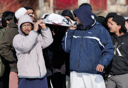 people carry a wrapped body to a grave