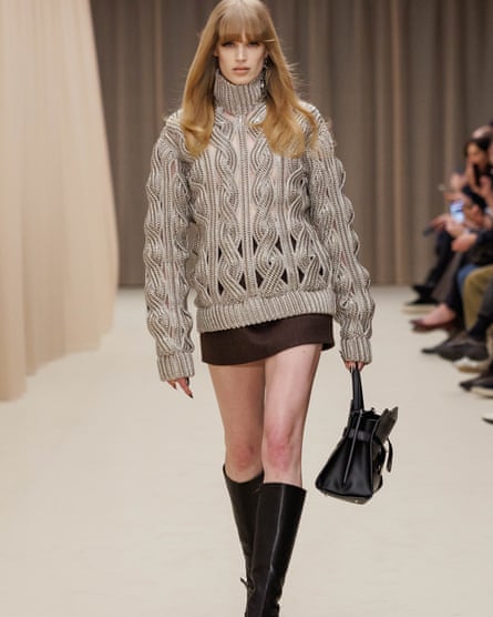 A model in an oversized knit, miniskirt and high boots