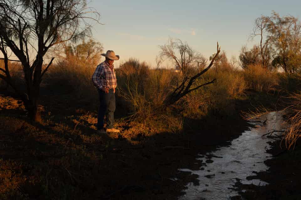 Dude Kidd watches as water from rains slowly runs down a gully on his property