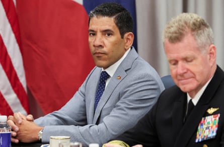 Man in gray suit sitting next to man with naval unit patches on black blazer