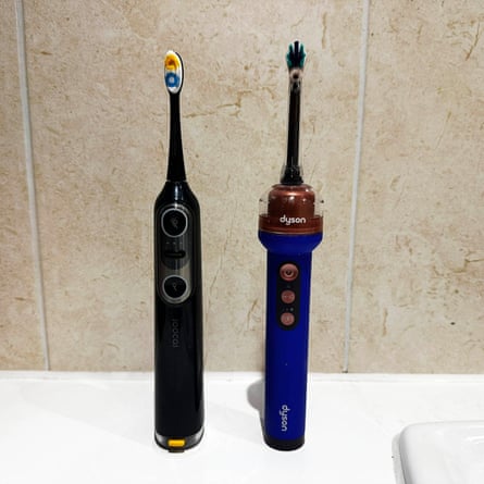 Two electric toothbrushes, Dyson and Soocas models, stand upright side by side
