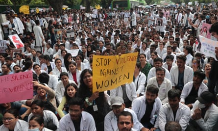 Doctors sitting down with banners, one reading: ‘Stop violence against women'