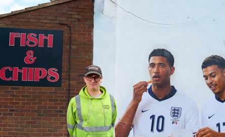 Artist Dion Kitson standing in front of the chippy with his mural in the background.