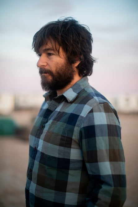 A man in blue plaid poses for a portrait