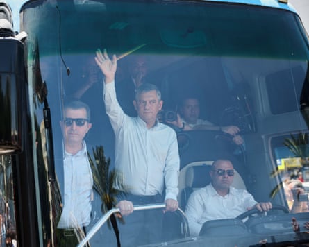 Özgür Özel waves through the front window of a bus